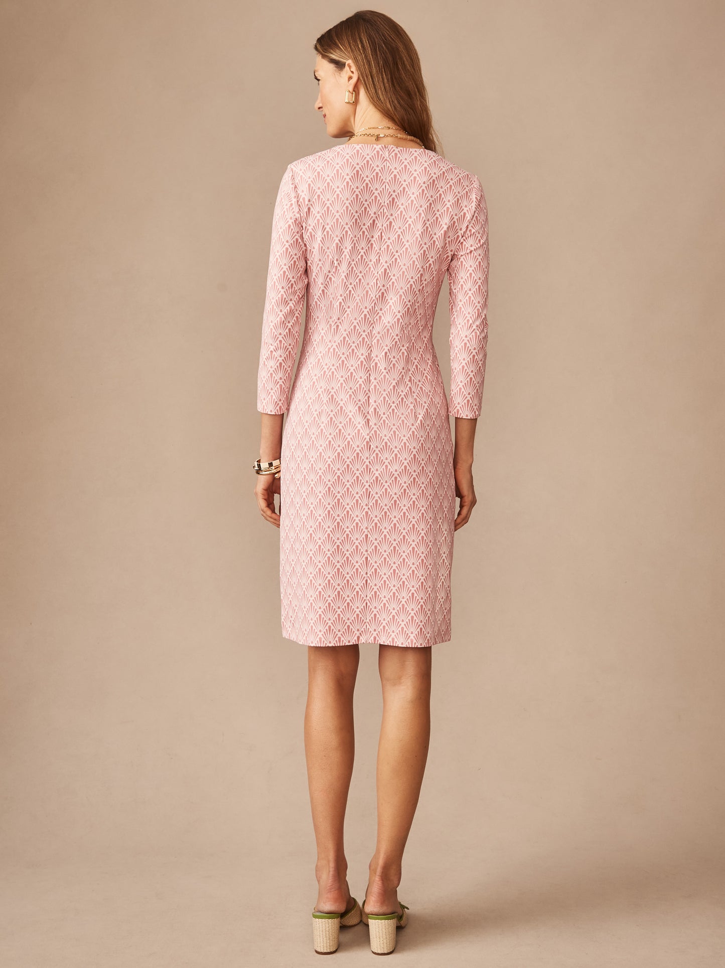 Woman models the back view of the Sophia Dress in Sandshell by J.McLaughlin, featuring a textured pink fabric and tailored silhouette, reflecting effortlessly stylish, enduring designs for a destination for defining style. Life, Well-Lived.