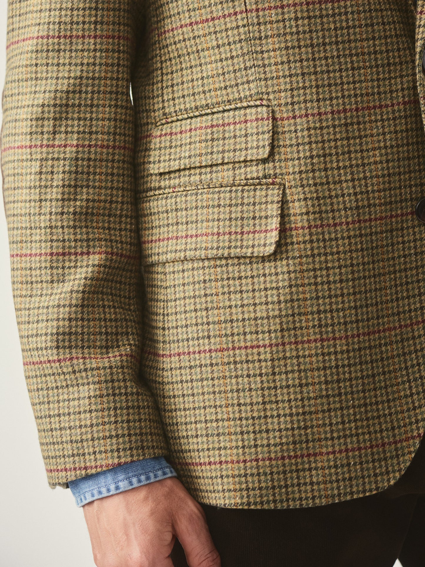 Model wearing J.McLaughlin Suffolk blazer in brown/green/red/mustard made with wool.