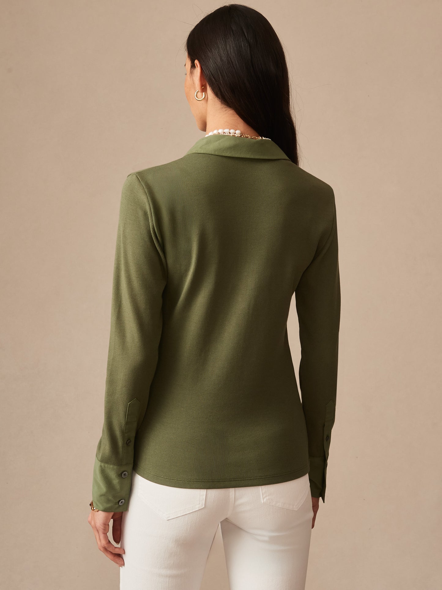 Woman wearing a moss green Theodora Shirt by J.McLaughlin, showcasing effortlessly stylish, enduring designs in innovative fabrics for a legacy of timeless fashion.