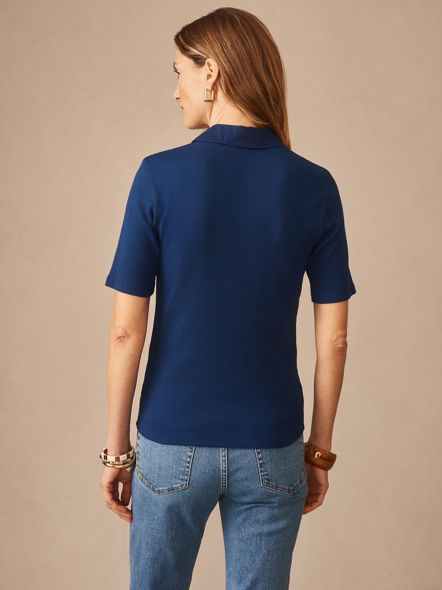Woman wearing a nautical navy Theodora Short Sleeve Shirt by J.McLaughlin, paired with denim jeans, showcasing effortlessly stylish, enduring designs and a legacy of timeless fashion.
