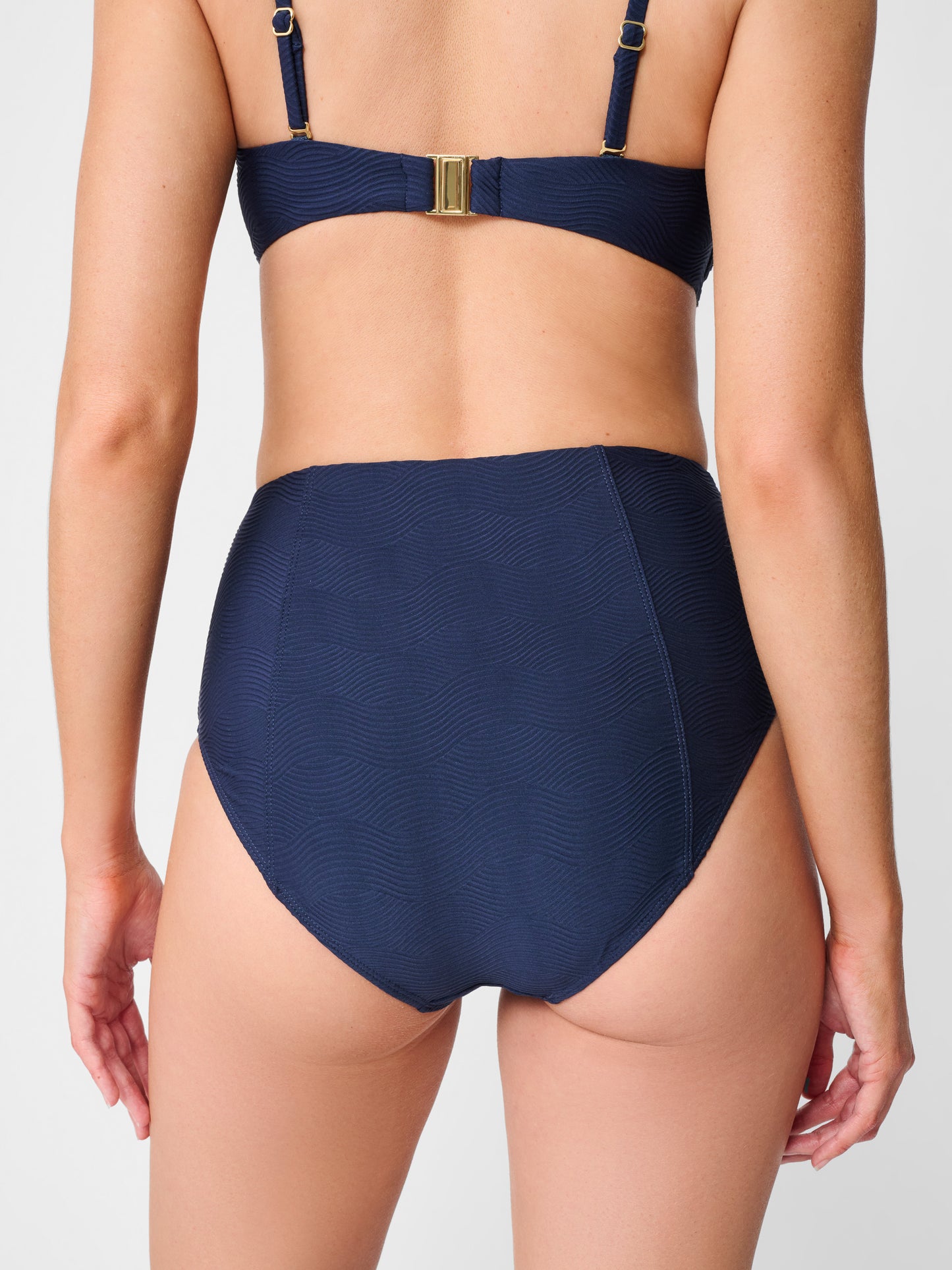 Model wearing J.McLaughlin Wailea bikini bottom in navy made with nylon and lycra.