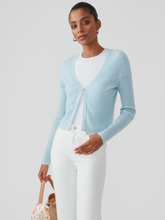 Woman wearing a baby blue Imogen Cashmere Cardigan by J.McLaughlin paired with white pants, showcasing effortlessly stylish, enduring designs and a legacy of timeless fashion.
