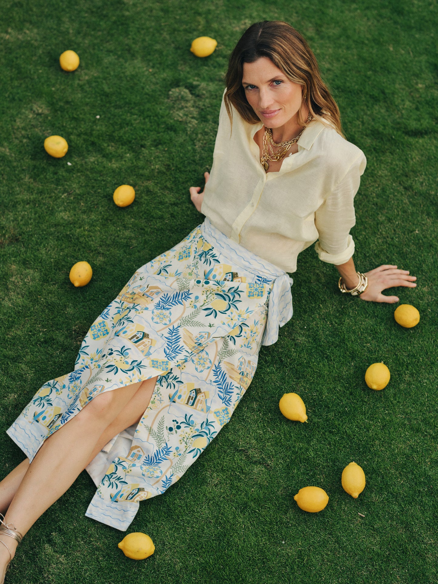 Woman lounging on grass wearing an effortlessly stylish Ardis Linen Blend Skirt in Amalfi Coast by J.McLaughlin, paired with a classic light blouse, showcasing enduring designs and innovative fabrics. A destination for defining style. Life, Well-Lived.