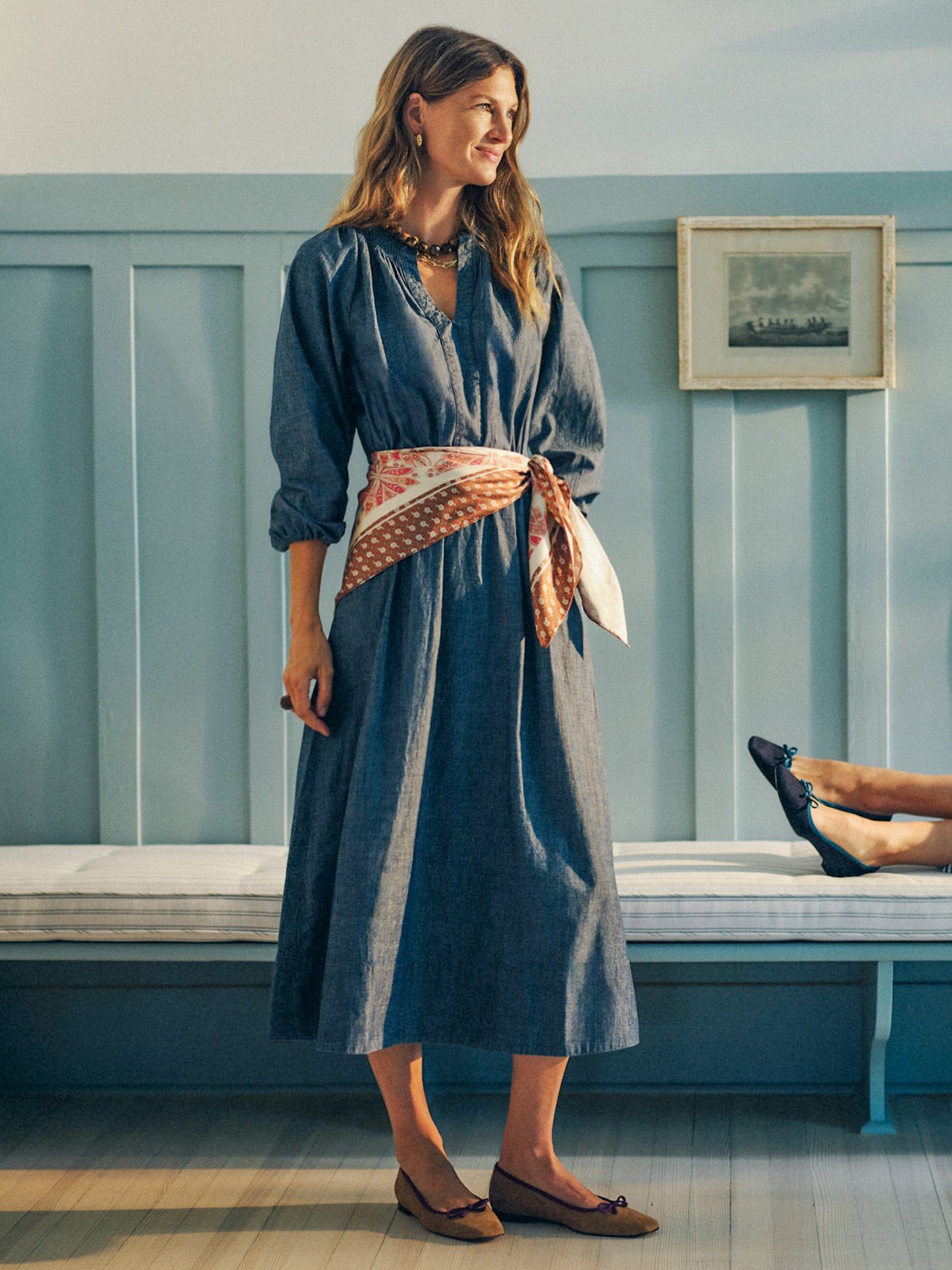 Woman wearing a Winslet Chambray Dress by J.McLaughlin styled with a patterned scarf belt and flats, embodying effortlessly stylish and enduring designs in a classic setting.