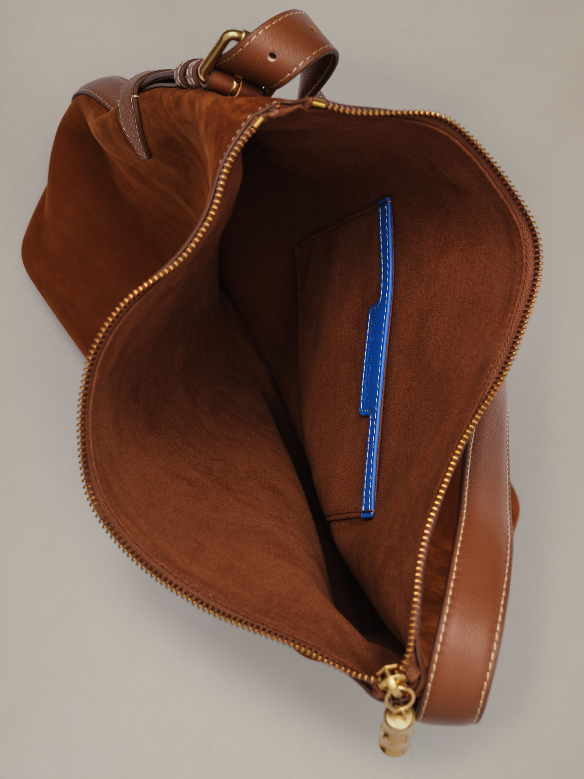 The Montecito Suede Hobo Bag by J.McLaughlin in rich brown suede shown open with a spacious interior and blue zip pocket