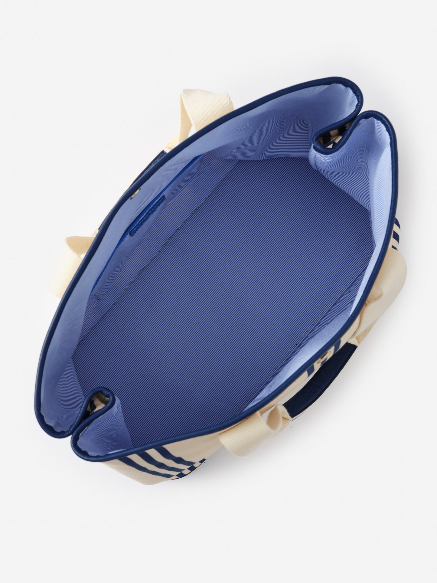 Top view of the Alma Canvas Tote in Stripe by J.McLaughlin showcasing its spacious interior with refined blue lining, reflecting effortlessly stylish, enduring designs and innovative fabrics.