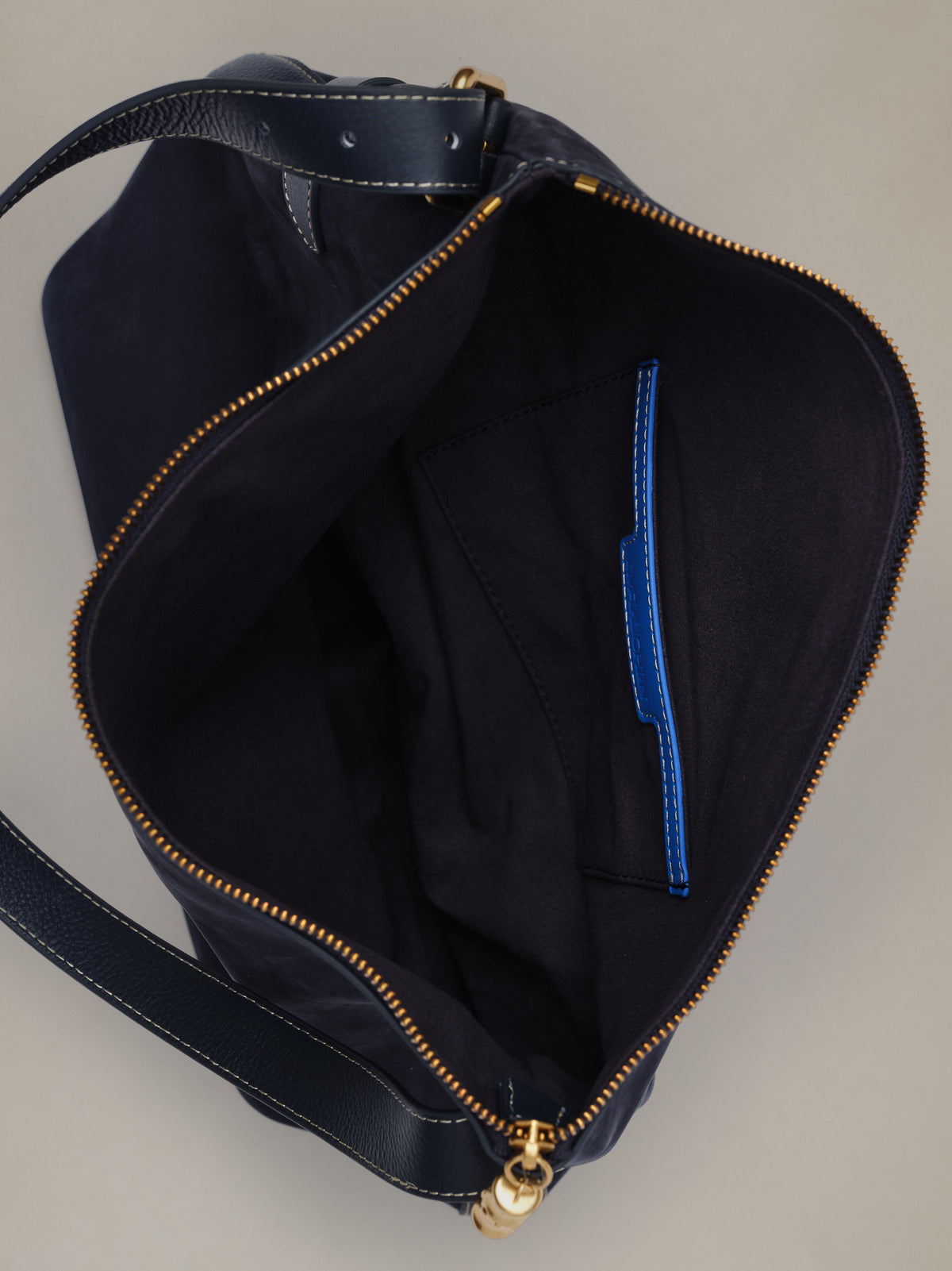 The Montecito Suede Hobo Bag by J.McLaughlin shown open with a spacious dark suede interior secure zip pocket and signature bamboo inspired zipper pull