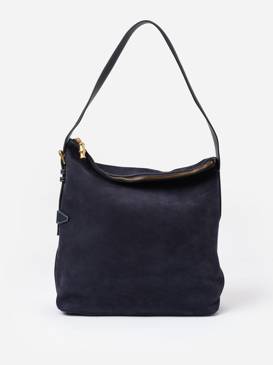 The Montecito Suede Hobo Bag by J.McLaughlin in deep navy suede features a bamboo-inspired zipper pull and a single shoulder strap, combining casual elegance with timeless style.
