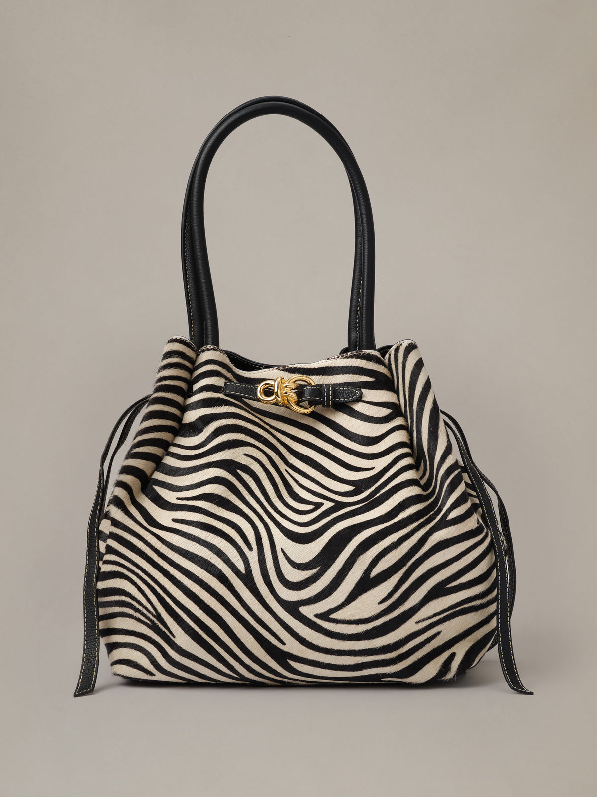 The Lex Pony Hair Tote Bag in Zebra Stripes by J.McLaughlin featuring a spacious zebra print design with black leather handles and gold-tone hardware