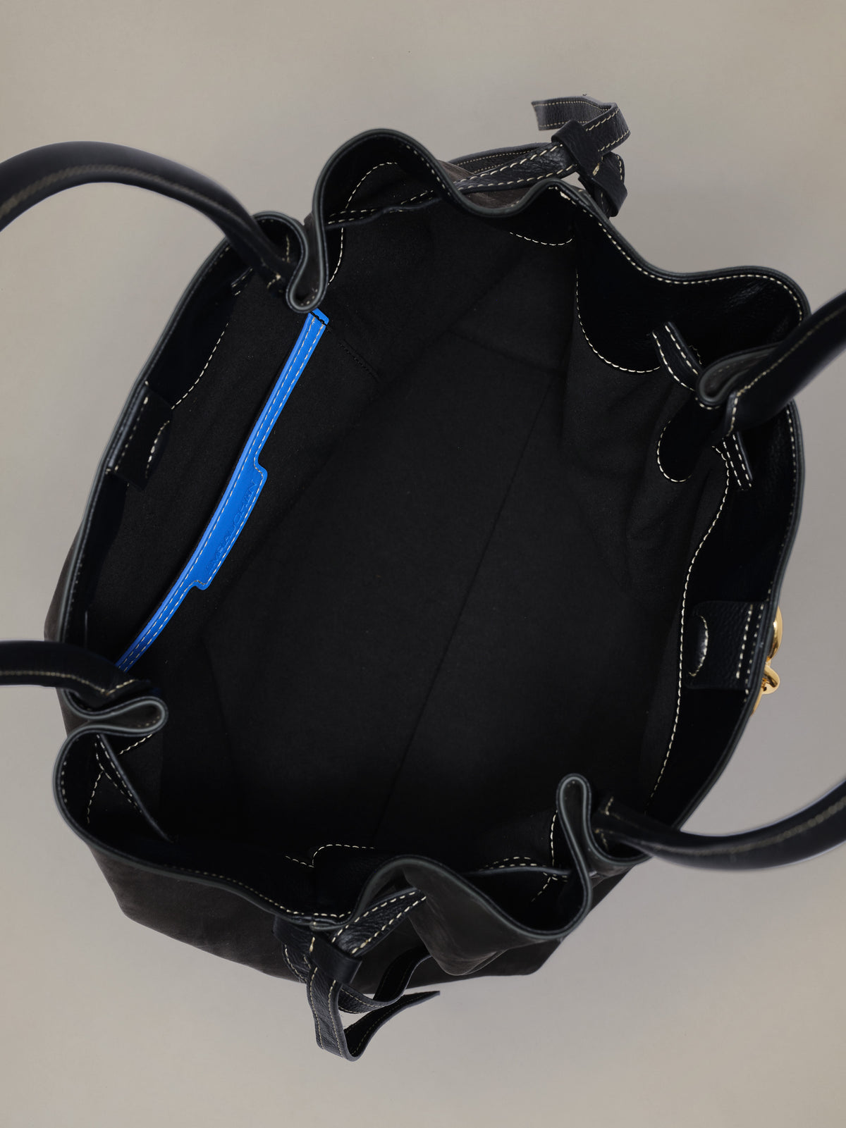 The Lex Suede Tote Bag by J.McLaughlin shown open revealing a spacious black suede interior with stitched details and an interior zip pocket