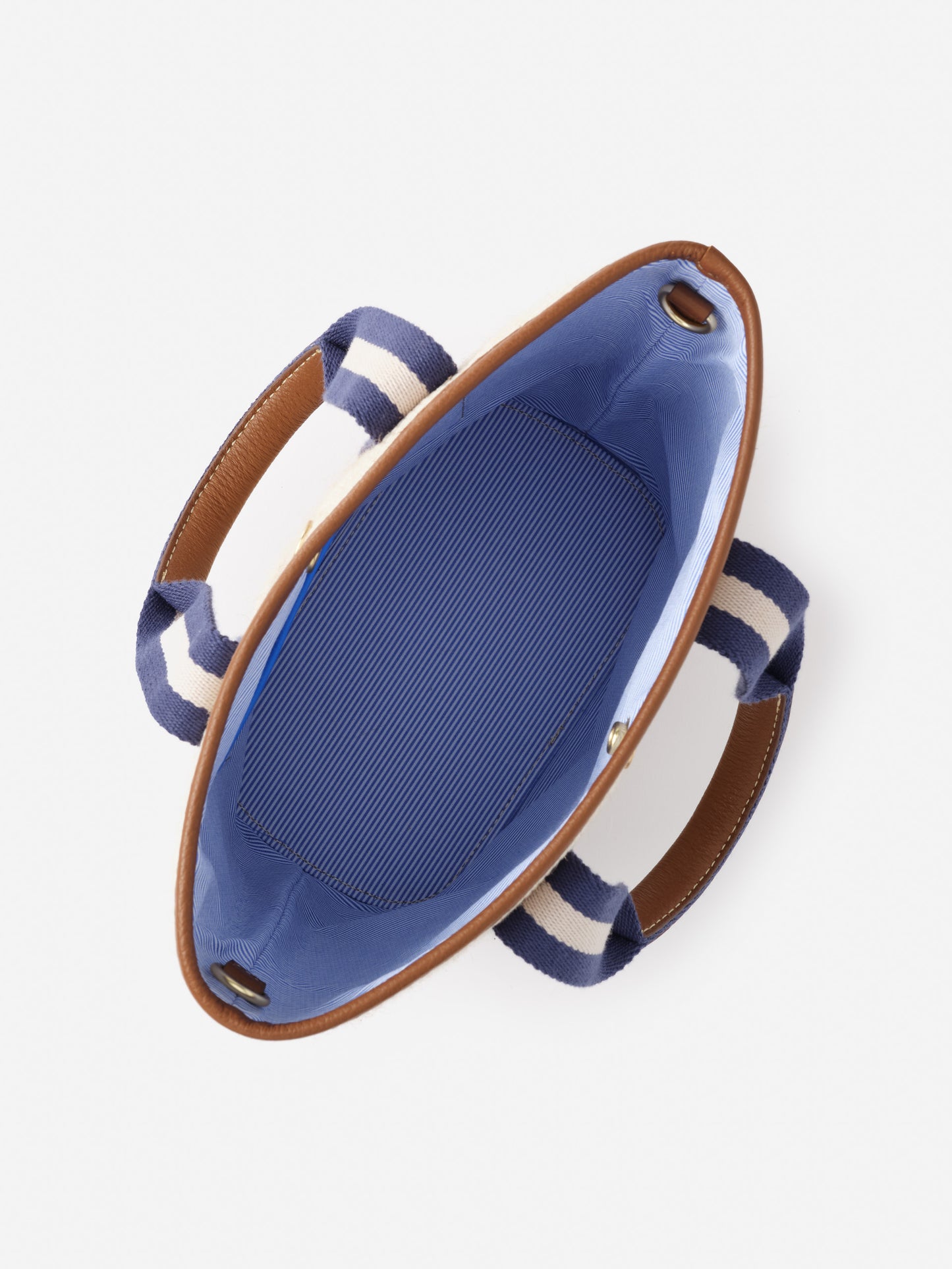 Open top view of the Emery Canvas Mini Tote by J.McLaughlin, featuring striped fabric handles, a blue interior, and brown leather trim showcasing impeccable craftsmanship and enduring design.