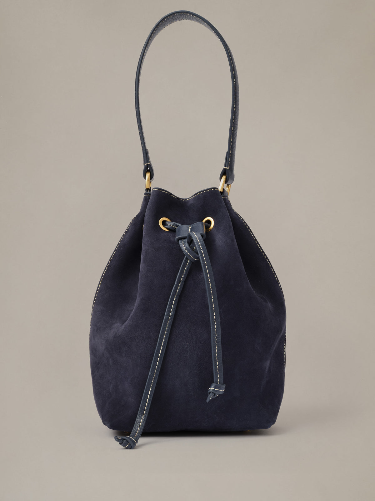 The Newbury Suede Bucket Bag by J.McLaughlin in dark navy suede with a drawstring closure and long shoulder strap