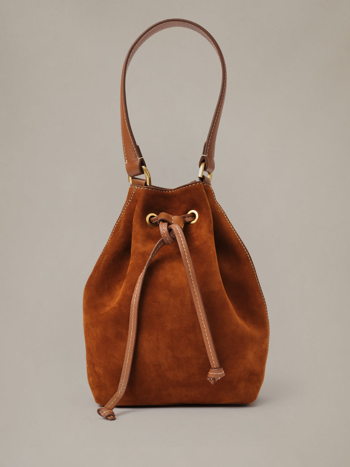 The Newbury Suede Bucket Bag by J.McLaughlin in rich brown suede with a drawstring closure and long shoulder strap