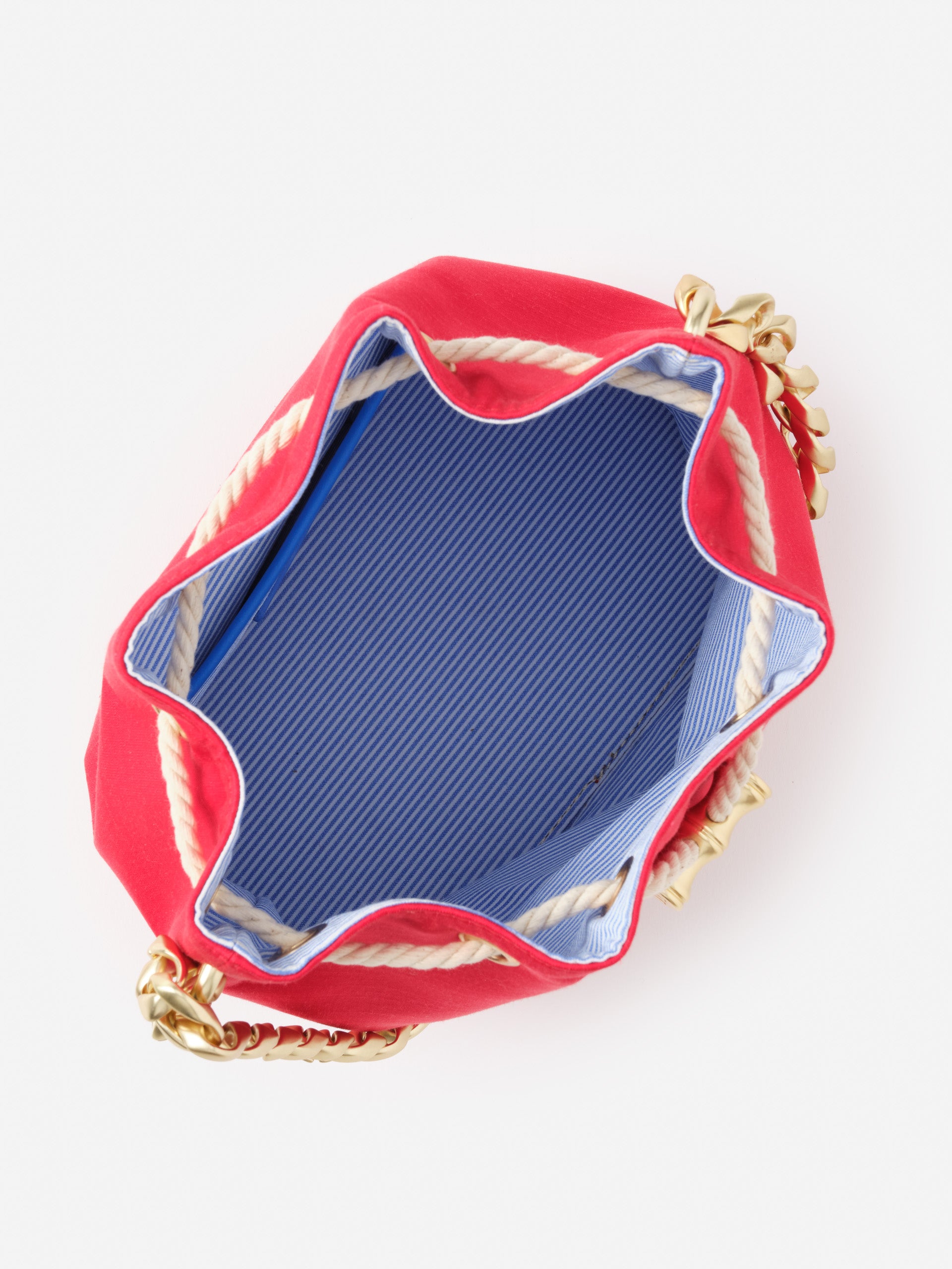 Interior view of the Sarah Bucket Bag by J.McLaughlin, showcasing a blue and white striped lining, gold chain strap, and rope trim, blending effortlessly stylish details with enduring designs.