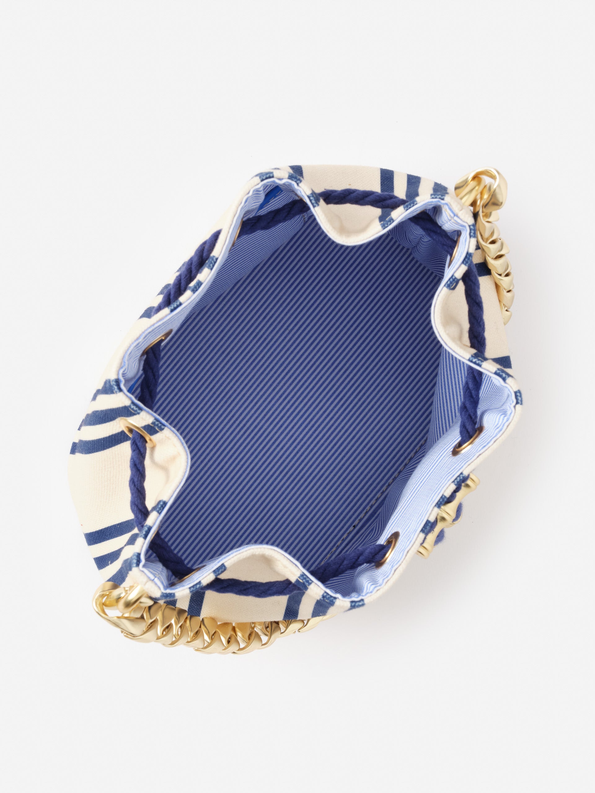 Interior view of the Daisy Canvas Bucket Bag in Stripe by J.McLaughlin, showcasing the classic striped fabric, rope drawstring closure, and gold-tone chain handles, reflecting effortlessly stylish, enduring designs and a legacy of timeless fashion. A destination for defining style. Life, Well-Lived.