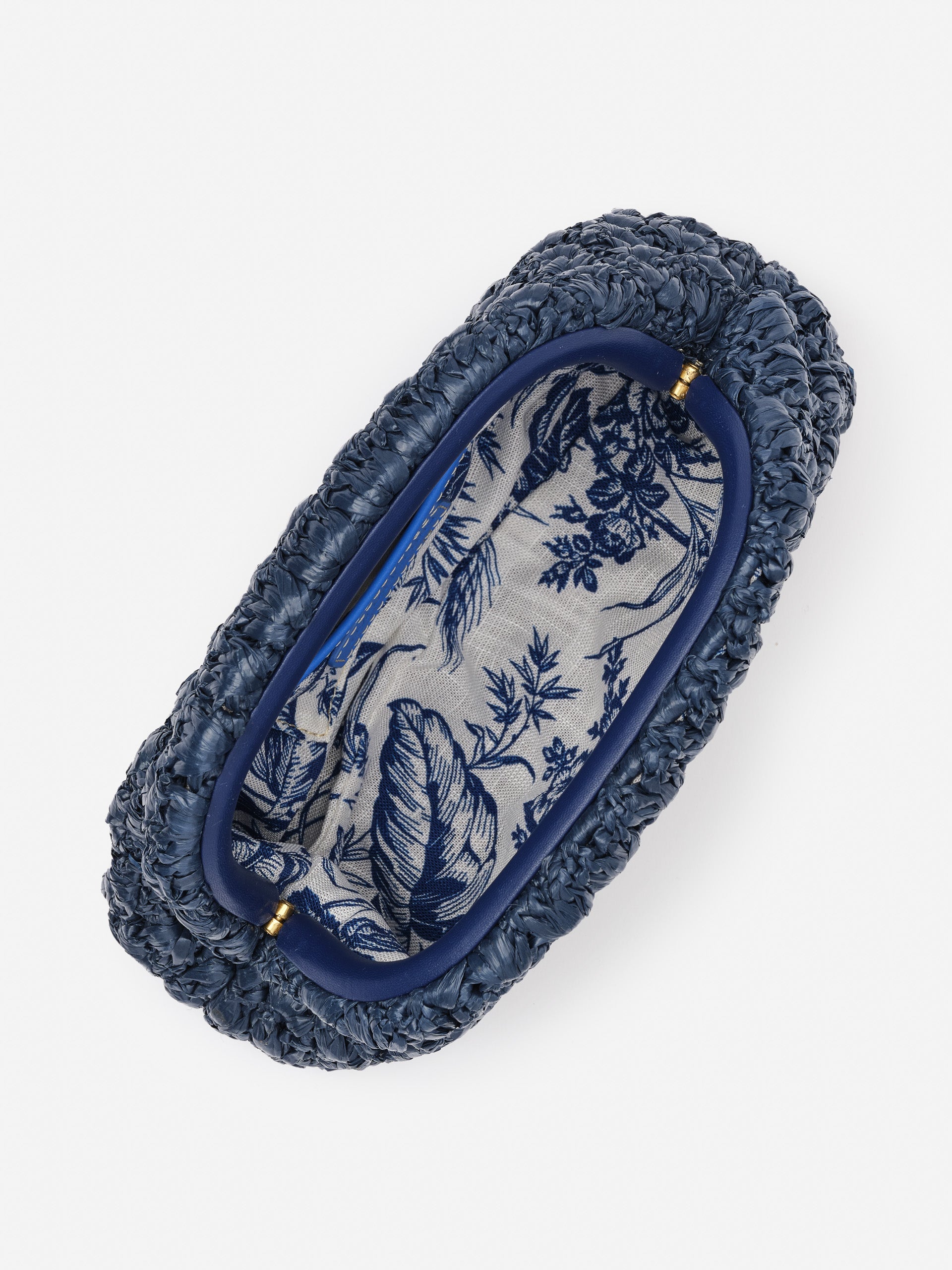 Top view of the Bambi Hand Crochet Clutch by J.McLaughlin, showcasing its deep blue crochet exterior and elegant floral fabric lining, embodying effortlessly stylish, enduring designs.
