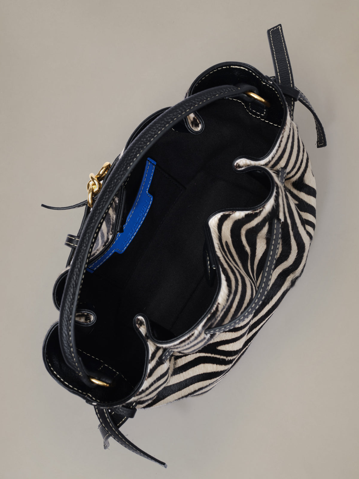 The Mini Lex Pony Hair Handbag in Zebra Stripes by J.McLaughlin shown from above with black leather trim gold hardware and a crossbody strap