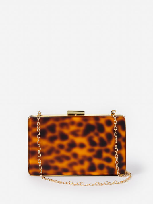 Audra Acrylic Clutch in Tortoise by J.McLaughlin features effortlessly stylish design with a tortoise pattern and gold chain, embodying enduring designs and a legacy of timeless fashion. A destination for defining style. Life, Well-Lived.