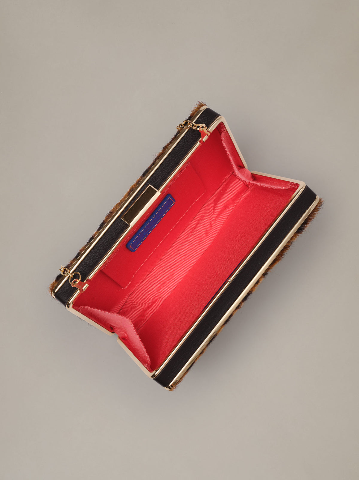 The Palm Pony Hair Clutch in Leopard by J.McLaughlin open showing a vivid red lined interior gold tone hardware and tuck away chain