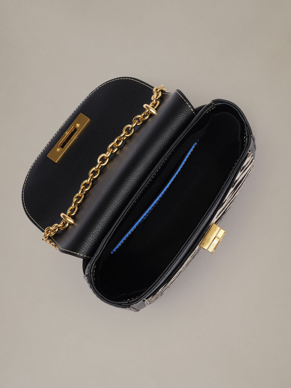 The Waverly Leather Handbag in Zebra Stripes by J.McLaughlin open to reveal a black interior gold chain strap and zebra striped sides