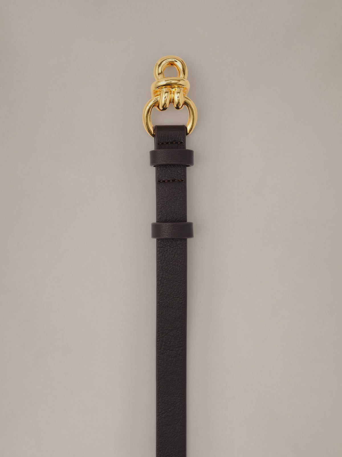 J.McLaughlin Natalie Leather Belt in black leather with signature gold knot hardware and slim profile for timeless everyday style.