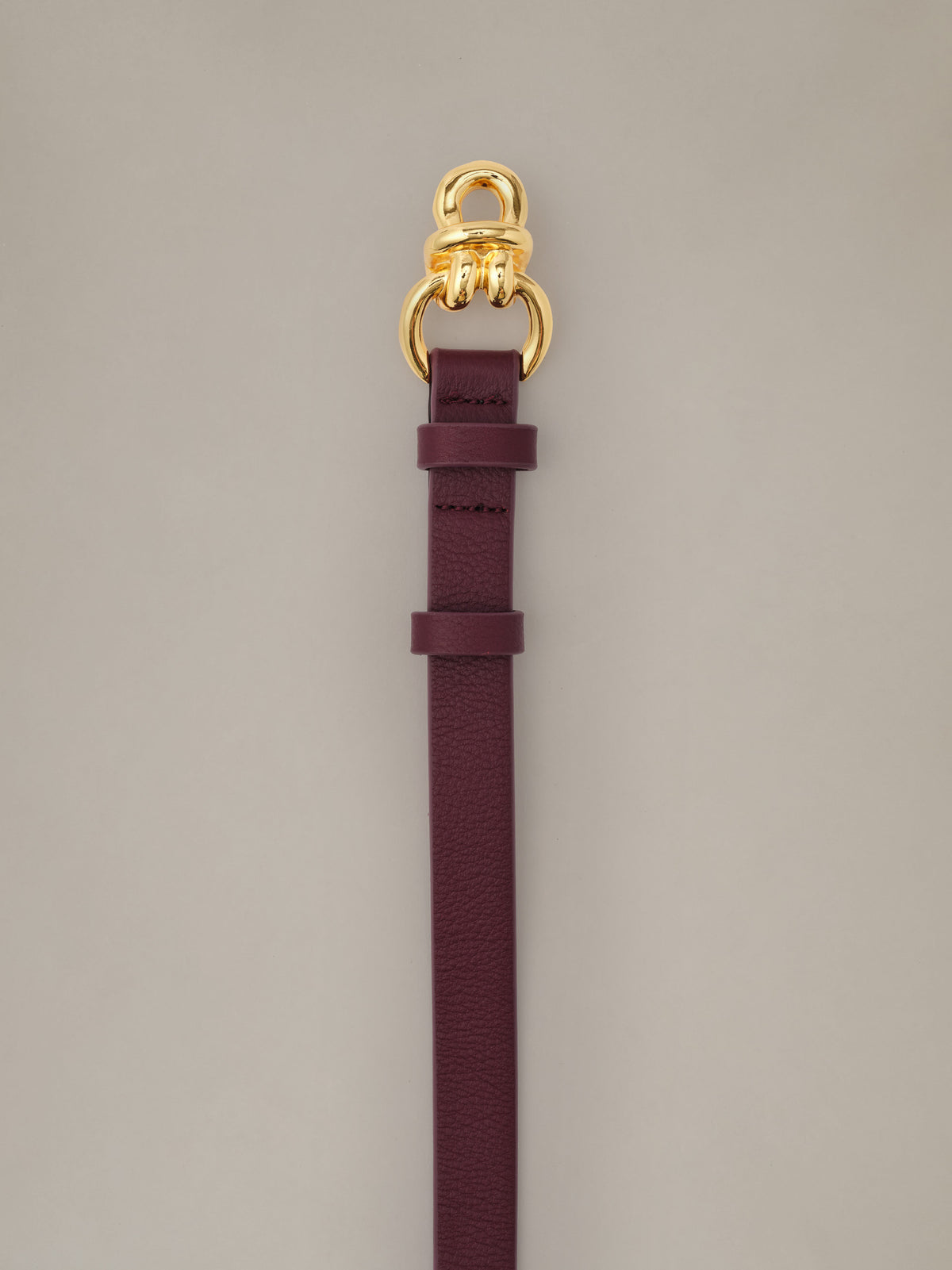 Natalie Leather Belt by J.McLaughlin in burgundy leather with signature gold knot hardware and a slim profile