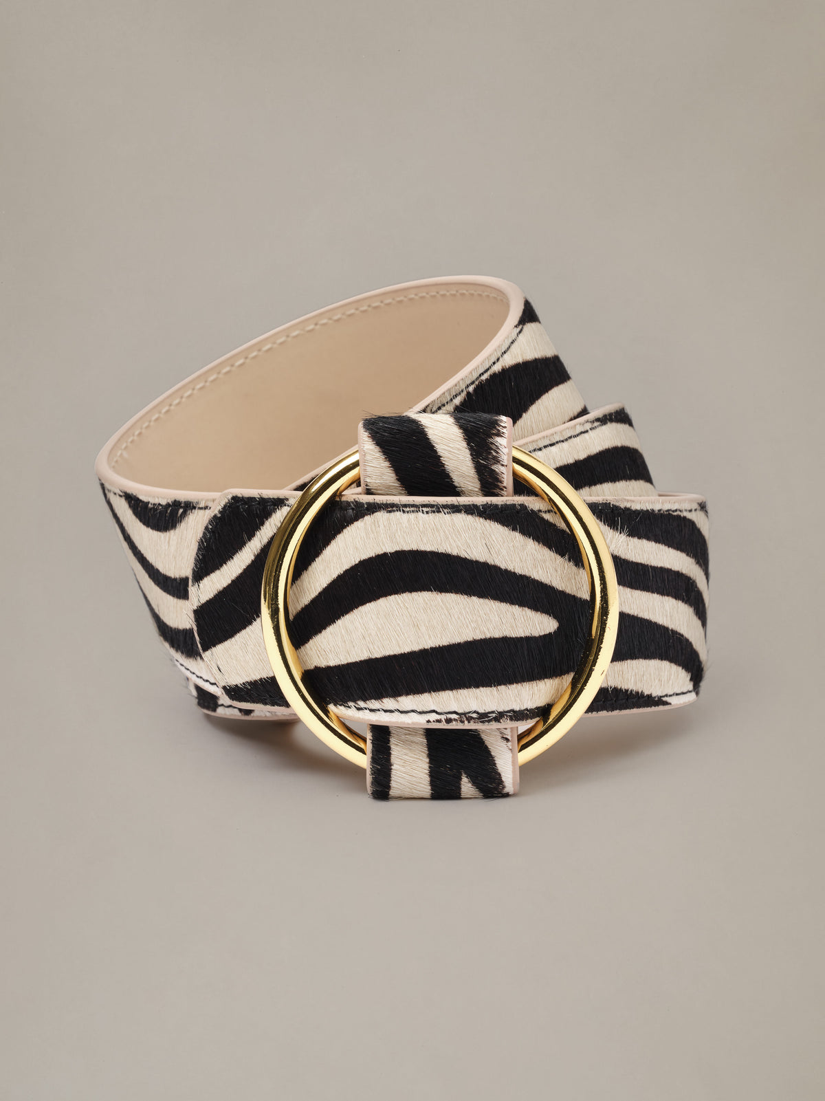 Amelia Pony Hair Belt in Zebra Stripes by J.McLaughlin featuring a wide zebra print design and polished gold round buckle on a neutral background