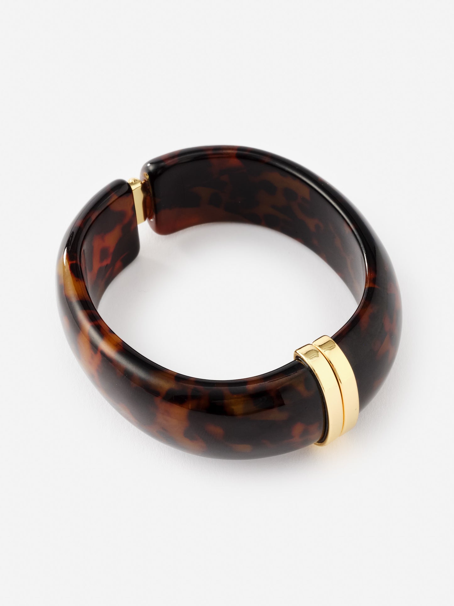 Resin Hinge Bangle by J.McLaughlin features an effortlessly stylish tortoiseshell design with gold-tone accents, reflecting enduring designs and a legacy of timeless fashion.