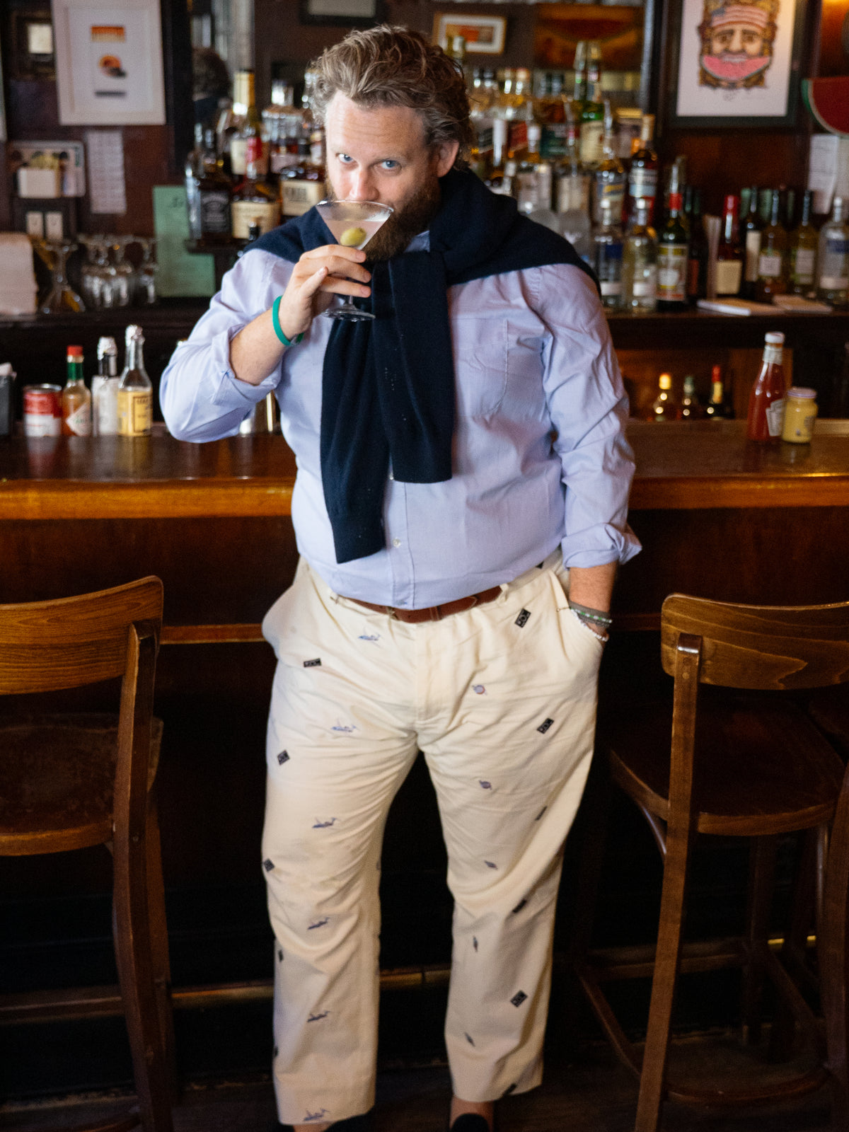 J.McLaughlin x Walksauce: Madison Embroidered Fancy Pants in Jet Set shown on a man at a bar with embroidered motifs and a relaxed tailored fit