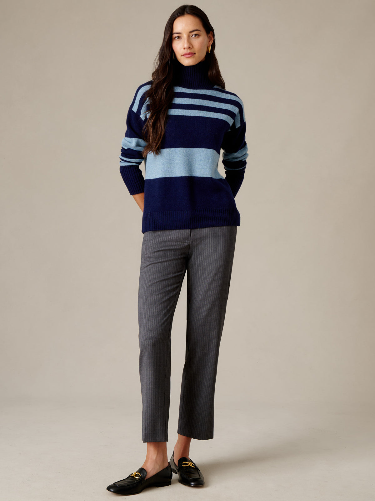 J.McLaughlin Dina Cashmere Turtleneck in Stripe worn with gray trousers and black loafers on a woman in a timeless studio fashion portrait