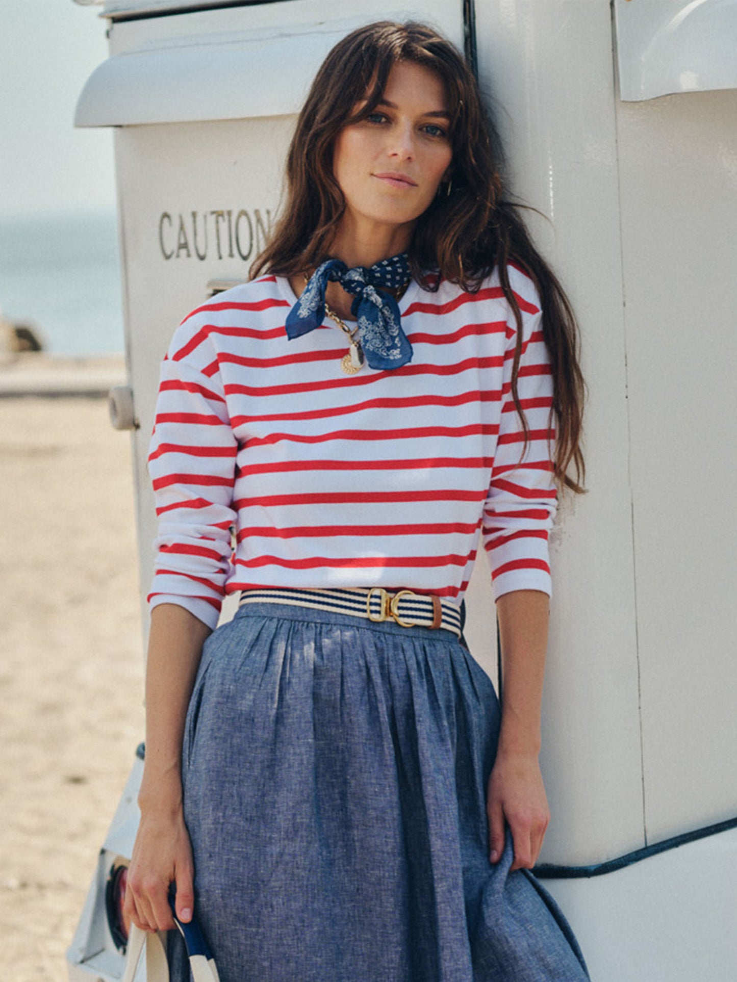 Woman wearing a red and white striped top paired with a blue skirt and accessorized with a Mini Isobel Canvas Belt in Stripe by J.McLaughlin, embodying effortlessly stylish, enduring designs.