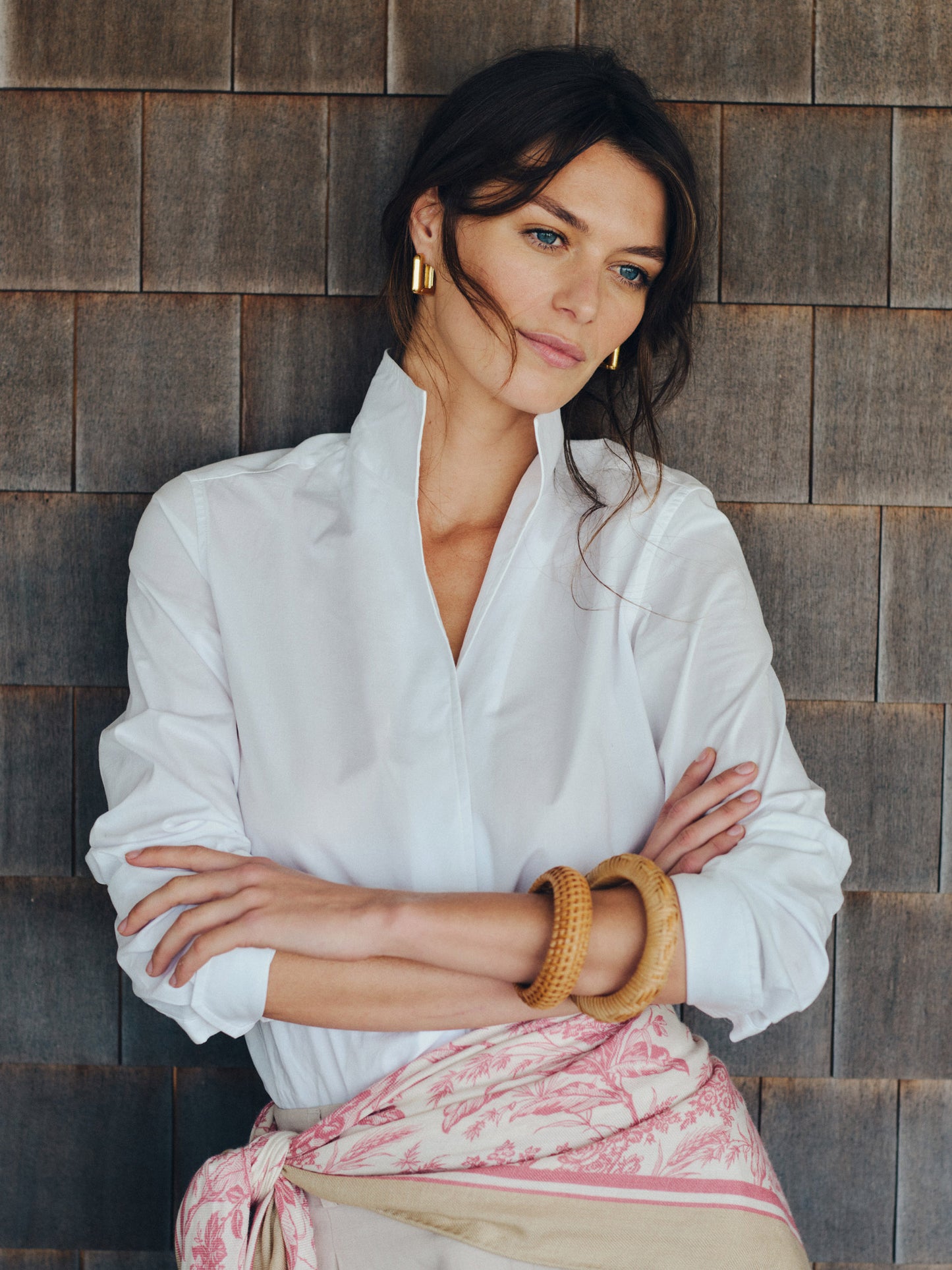 Woman wearing a white Victoria Shirt by J.McLaughlin, styled with gold hoop earrings and natural-toned bangles, embodying effortlessly stylish, enduring designs and innovative fabrics.