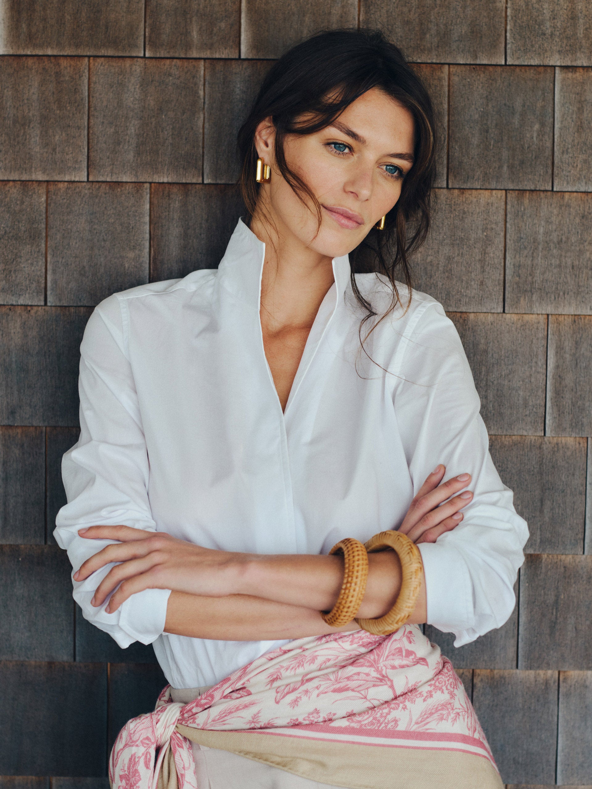 Woman wearing a white Victoria Shirt by J.McLaughlin, styled with gold hoop earrings and natural-toned bangles, embodying effortlessly stylish, enduring designs and innovative fabrics.