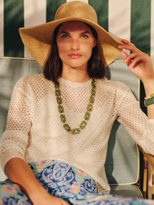 Woman wearing a Philomena Cashmere Linen Sweater by J.McLaughlin, paired with a wide-brimmed straw hat and vibrant patterned pants, embodying effortlessly stylish, enduring designs.