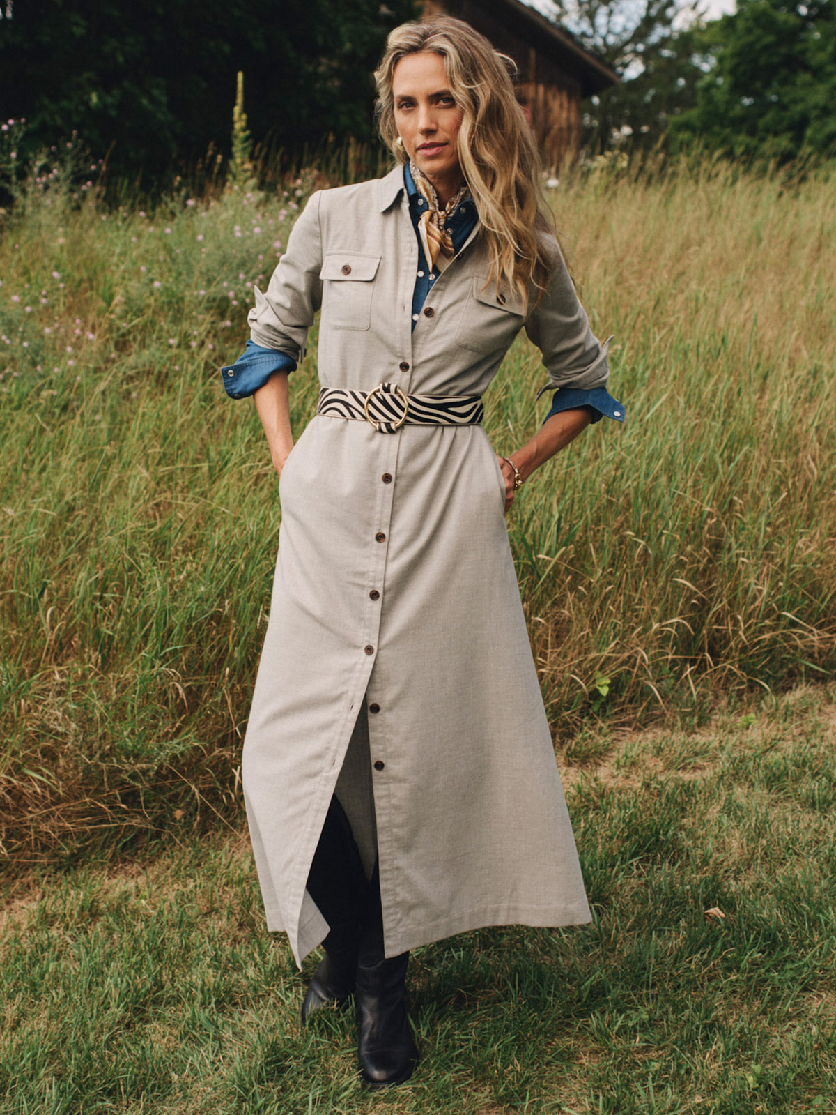 J.McLaughlin Fallon Dress in a soft beige shirt dress with chest flap pockets rolled sleeves and a striped belt styled with black boots in a meadow