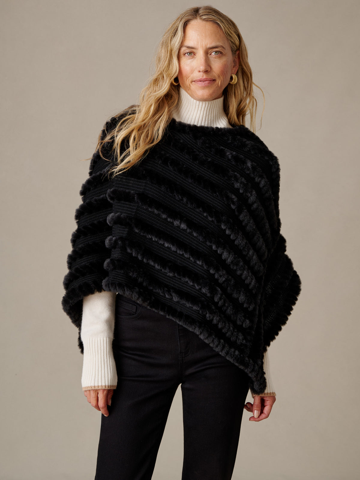 J.McLaughlin Charlie Faux Fur Poncho in black textured faux fur styled over a white sweater and black pants for timeless winter elegance