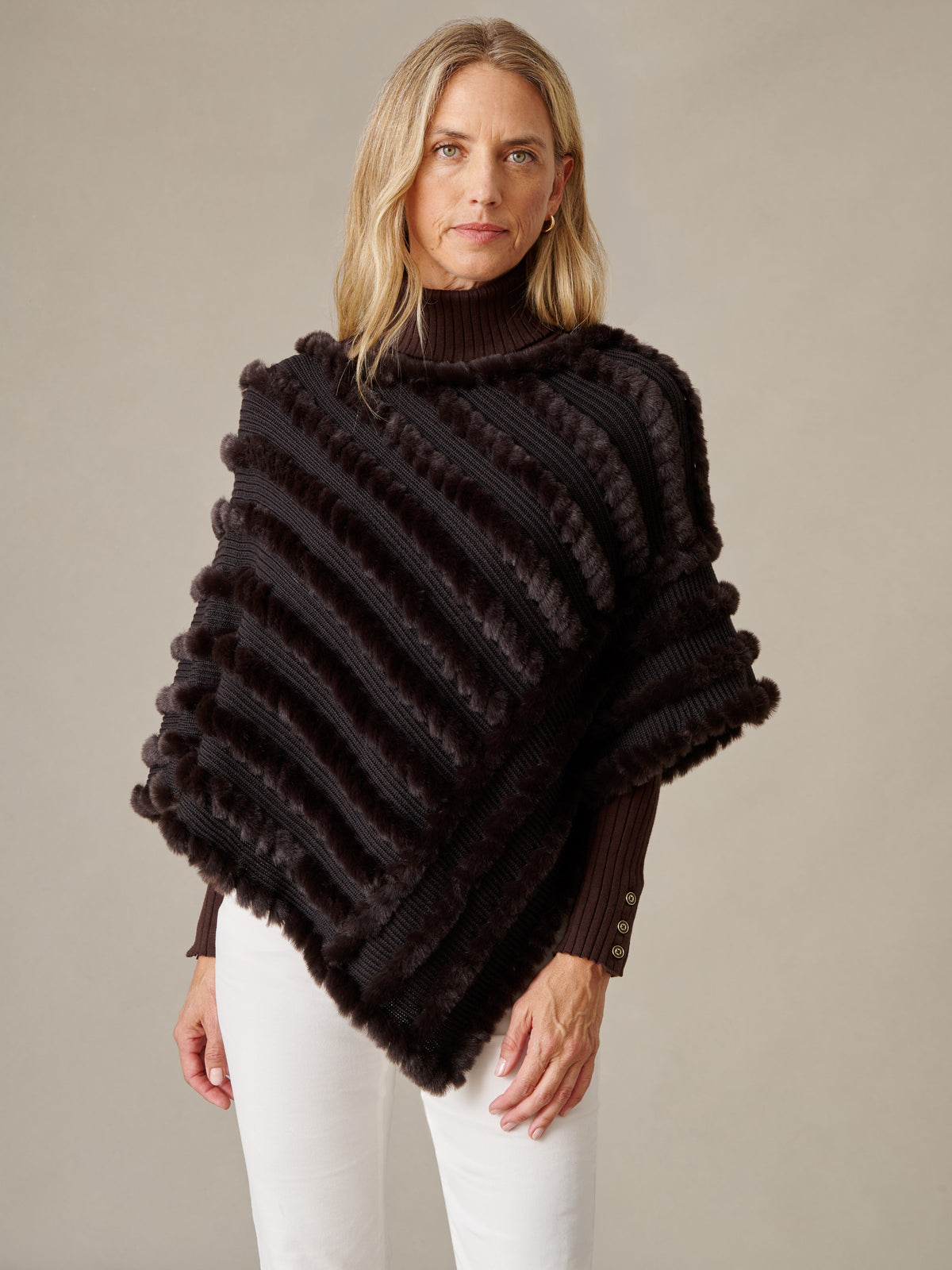 J.McLaughlin Charlie Faux Fur Poncho in dark brown faux fur worn by a model with white pants for a timeless winter look