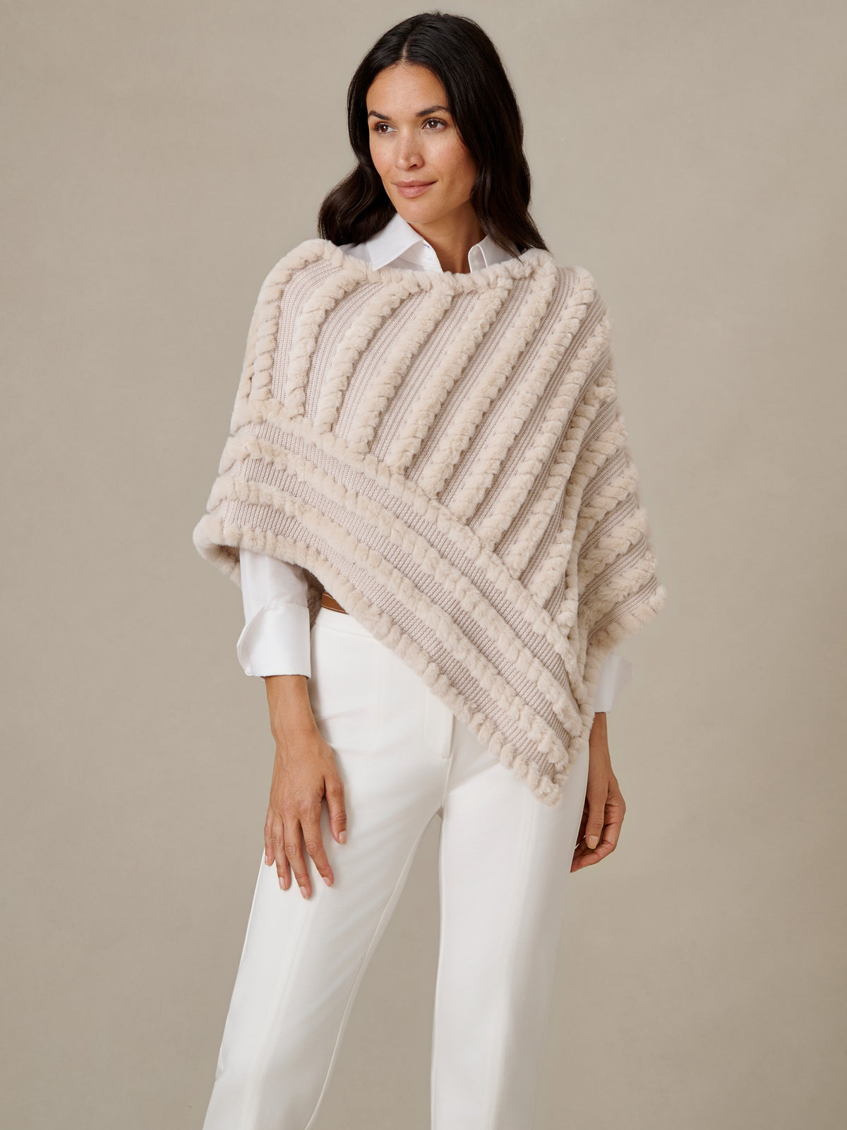 J.McLaughlin Charlie Faux Fur Poncho in ivory with textured diagonal stripes styled over a white blouse and pants for timeless winter elegance.
