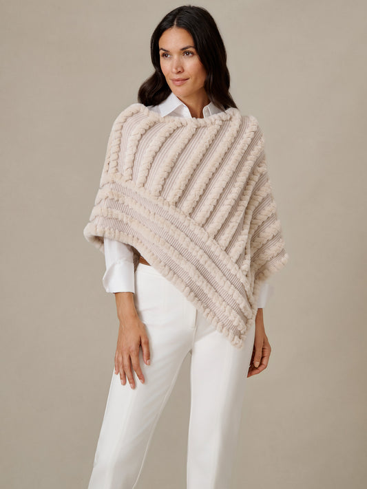 J.McLaughlin Charlie Faux Fur Poncho in ivory with textured diagonal stripes styled over a white blouse and pants for timeless winter elegance.