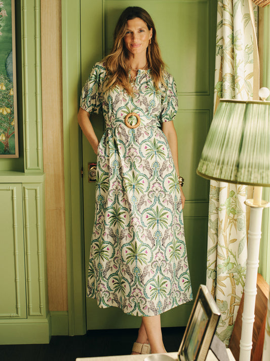 Woman wearing Marley Dress in Zebra Isle by J.McLaughlin featuring elegant green botanical print, standing in a stylish room with green walls and soft natural light, embodying effortlessly stylish, enduring designs with a legacy of timeless fashion, a destination for defining style. Life, Well-Lived.
