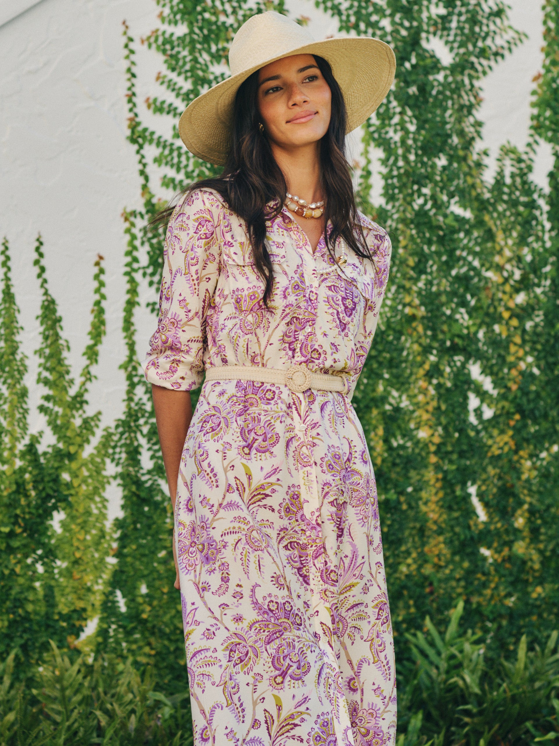 Woman wearing a Freda Dress in Maxi Heirloom Paisley by J.McLaughlin, styled with a wide-brimmed hat and layered necklaces, embodying effortlessly stylish and enduring designs.