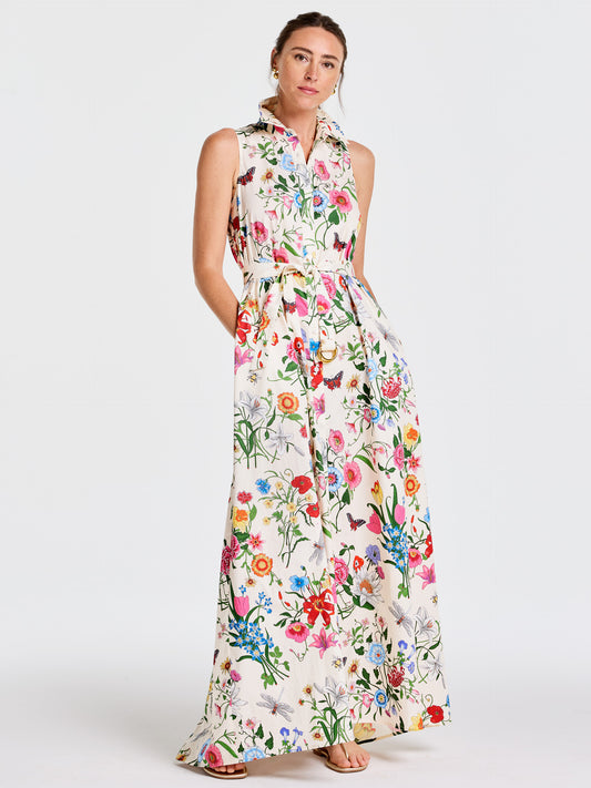 Woman wearing a sleeveless, full-length Audrey Dress in Dragonfly Garden by J.McLaughlin, featuring a vibrant floral and butterfly print with a belted waist, embodying effortlessly stylish, enduring designs and innovative fabrics.