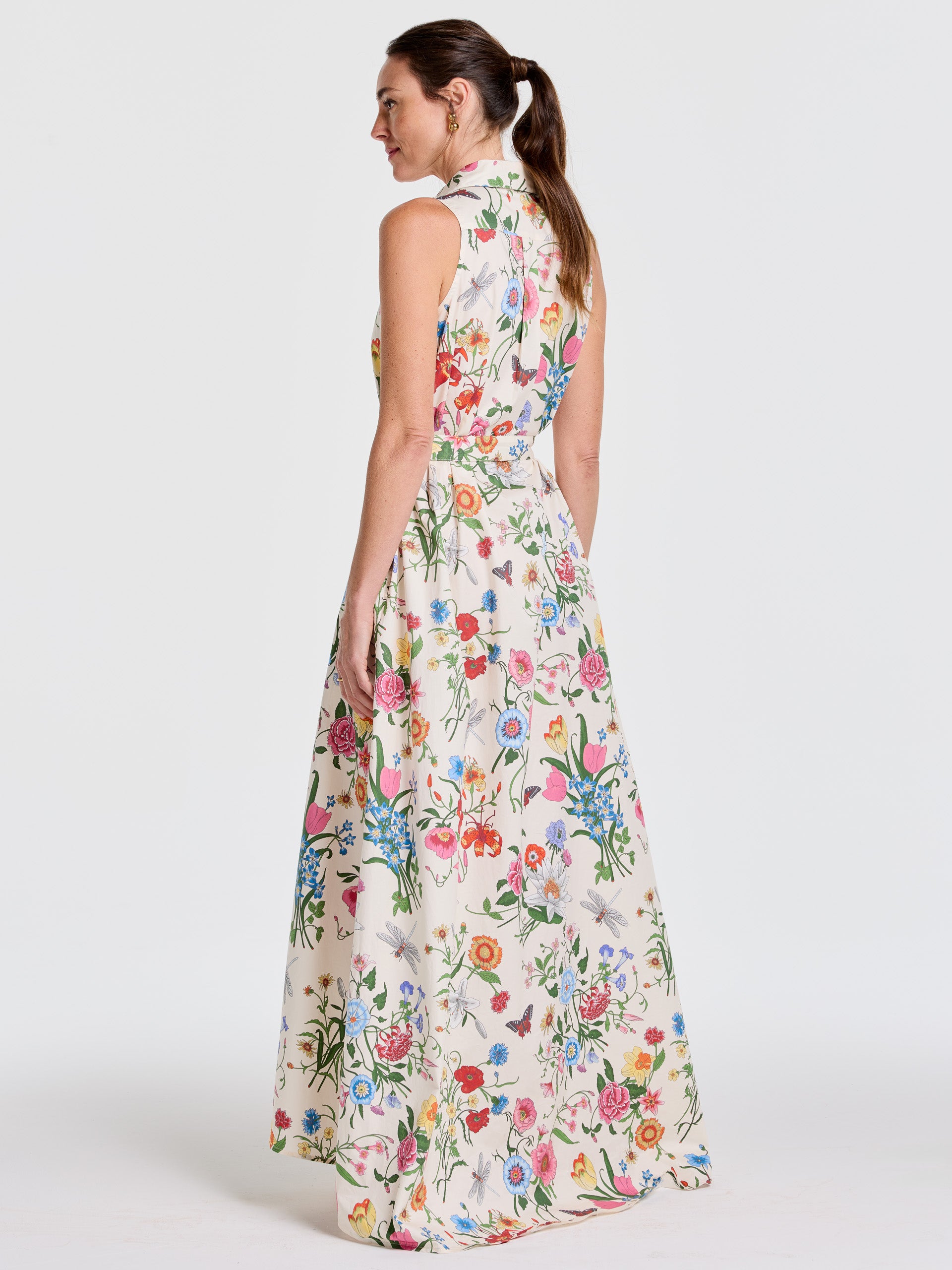 Woman wearing the Audrey Dress in Dragonfly Garden by J.McLaughlin, a sleeveless, floral-printed maxi dress with a high collar, showcasing effortlessly stylish, enduring designs in innovative fabrics for a legacy of timeless fashion. A destination for defining style. Life, Well-Lived.