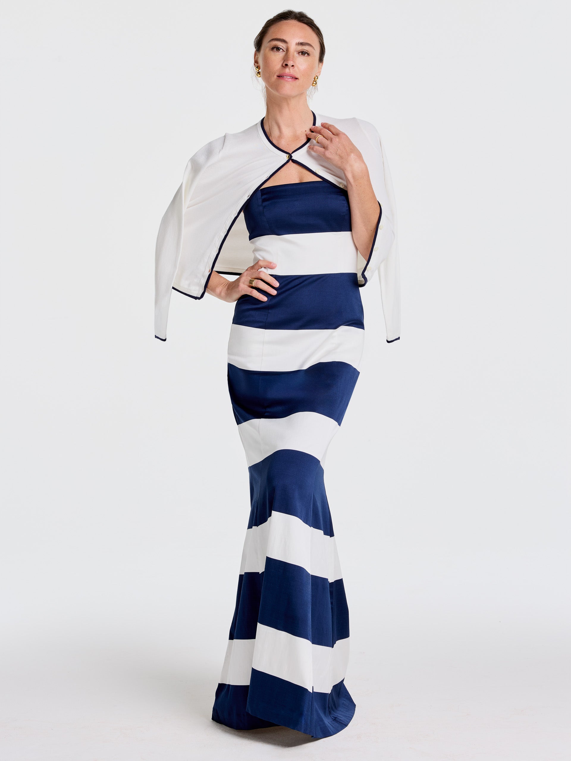 Woman wearing a navy and white striped dress paired with an off-white Aileen Cardigan by J.McLaughlin, showcasing effortlessly stylish, enduring designs for a life well-lived.