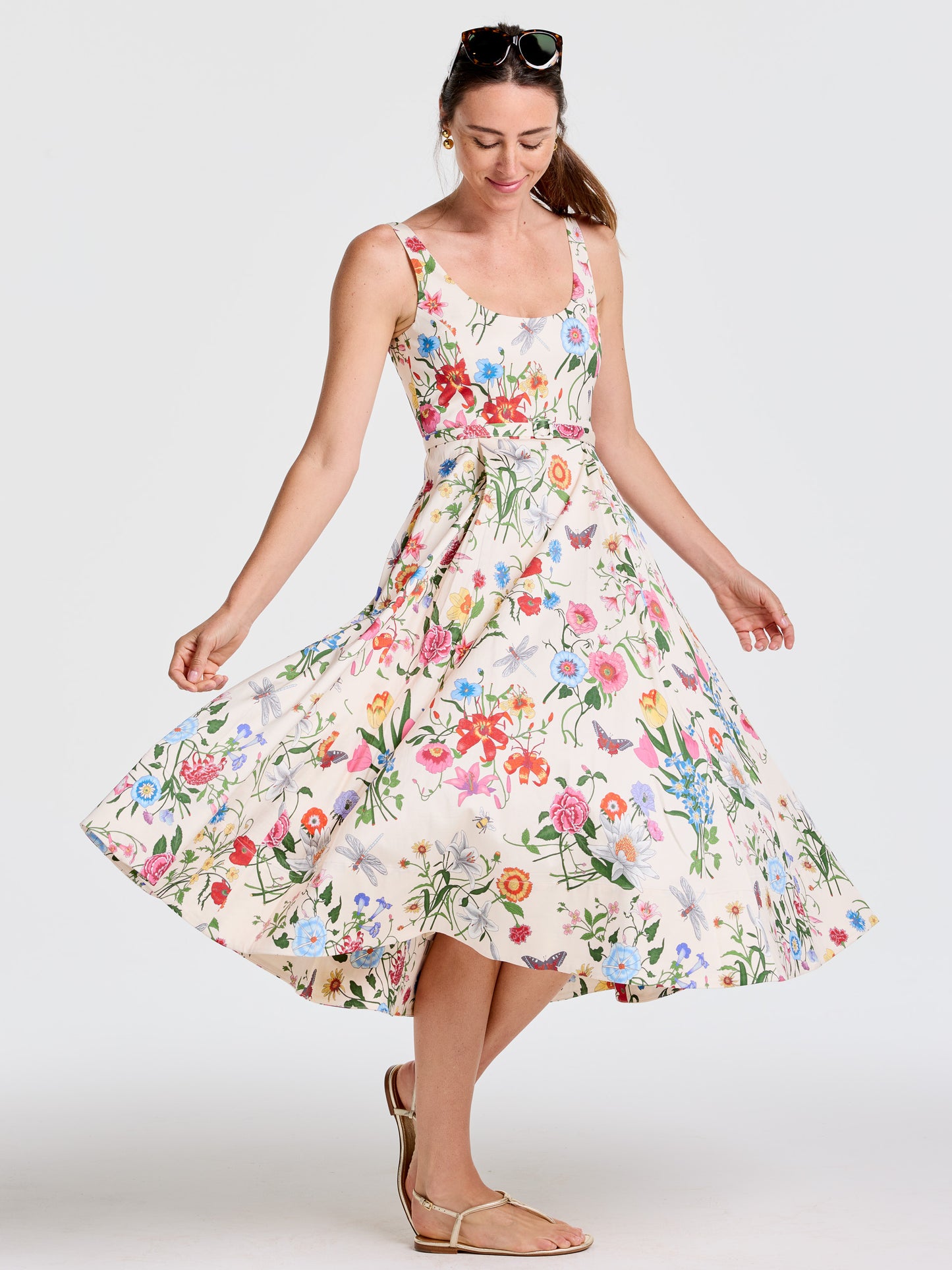 Woman wearing a sleeveless Charlotte Dress in Dragonfly Garden by J.McLaughlin, featuring a colorful floral print and flowing skirt, effortlessly stylish with enduring designs.