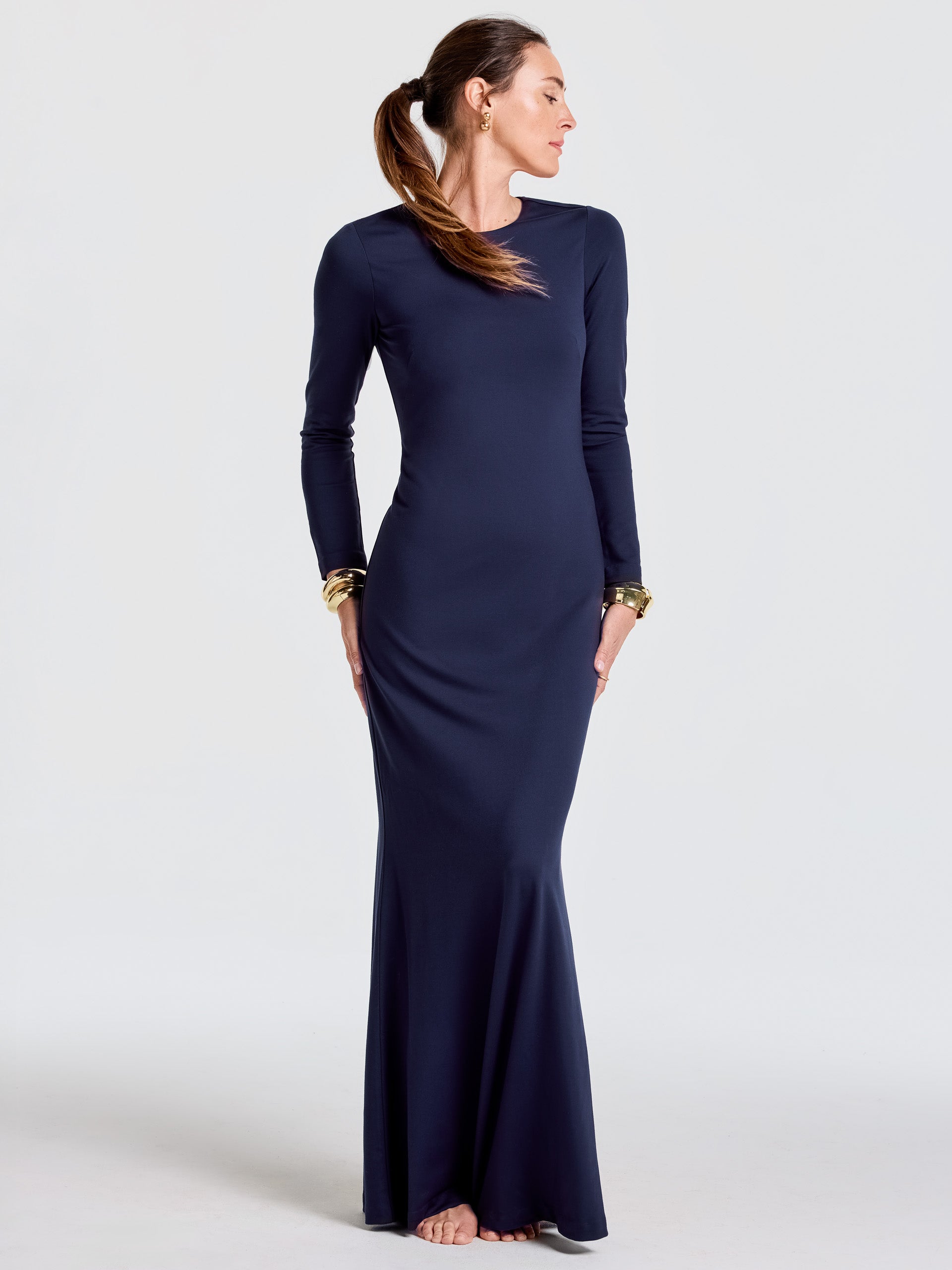 Woman wearing a navy Alexandra Dress by J.McLaughlin, featuring long sleeves and a sleek, floor-length silhouette that captures effortlessly stylish, enduring designs with a legacy of timeless fashion.