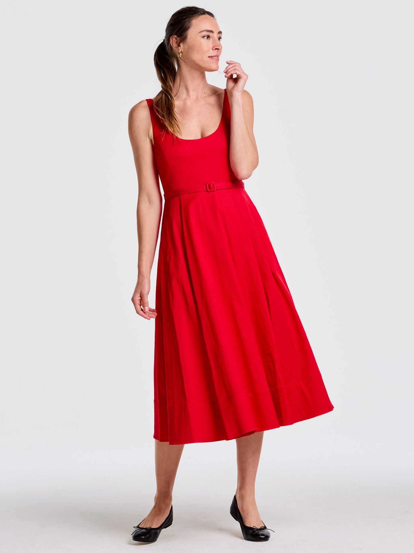 Woman wearing a vibrant red Charlotte Dress by J.McLaughlin, featuring a belted waist and flowing skirt, embodying effortlessly stylish, enduring designs with a legacy of timeless fashion.