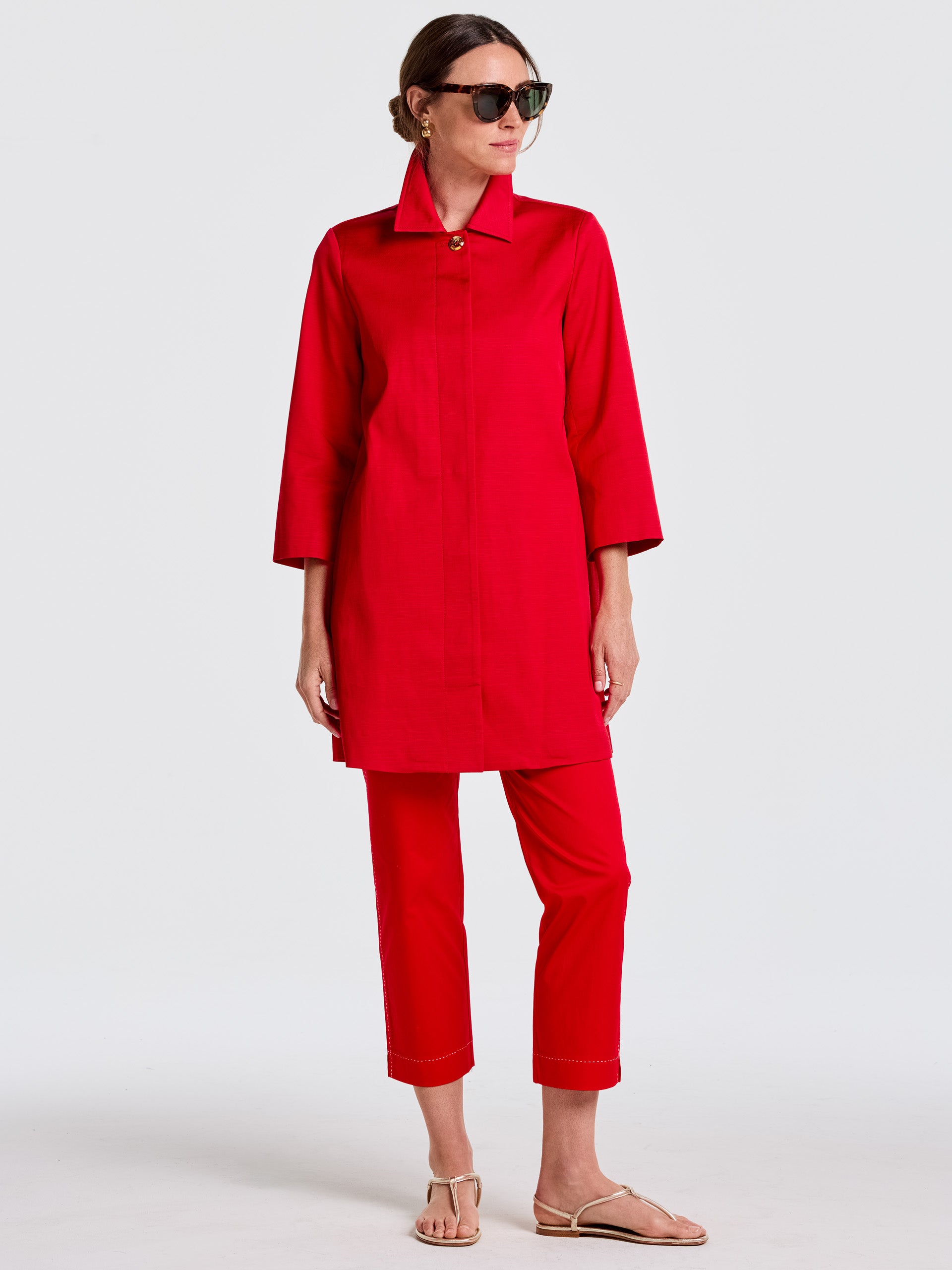 Woman wearing a vibrant red Emma Coat paired with matching cropped pants, styled with sunglasses and sandals, showcasing J.McLaughlin's effortlessly stylish, enduring designs and legacy of timeless fashion. A destination for defining style. Life, Well-Lived.