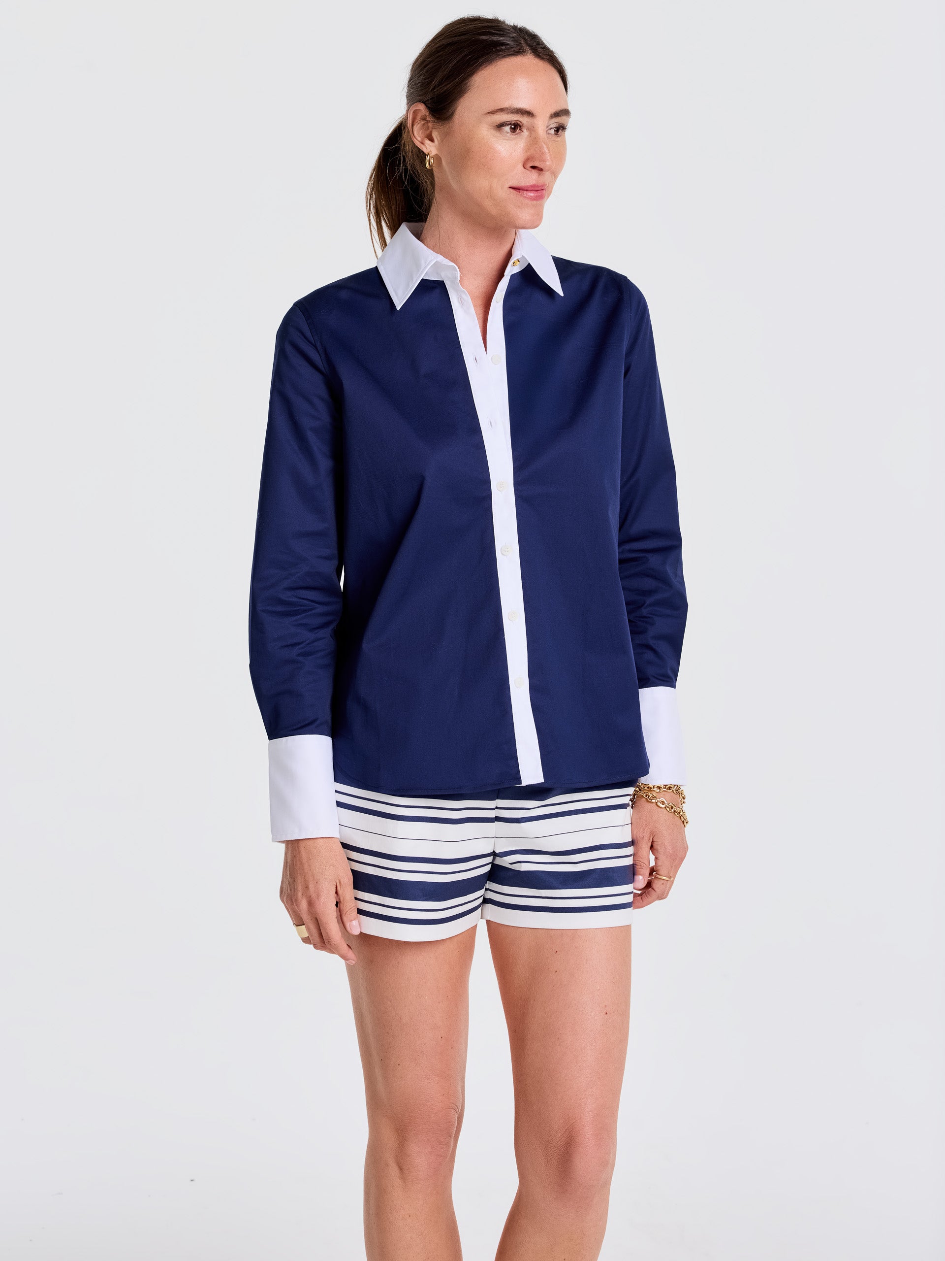 Woman wearing a navy and white Karla Shirt by J.McLaughlin paired with striped shorts, showcasing effortlessly stylish design and enduring appeal from a destination for defining style. Life, Well-Lived.