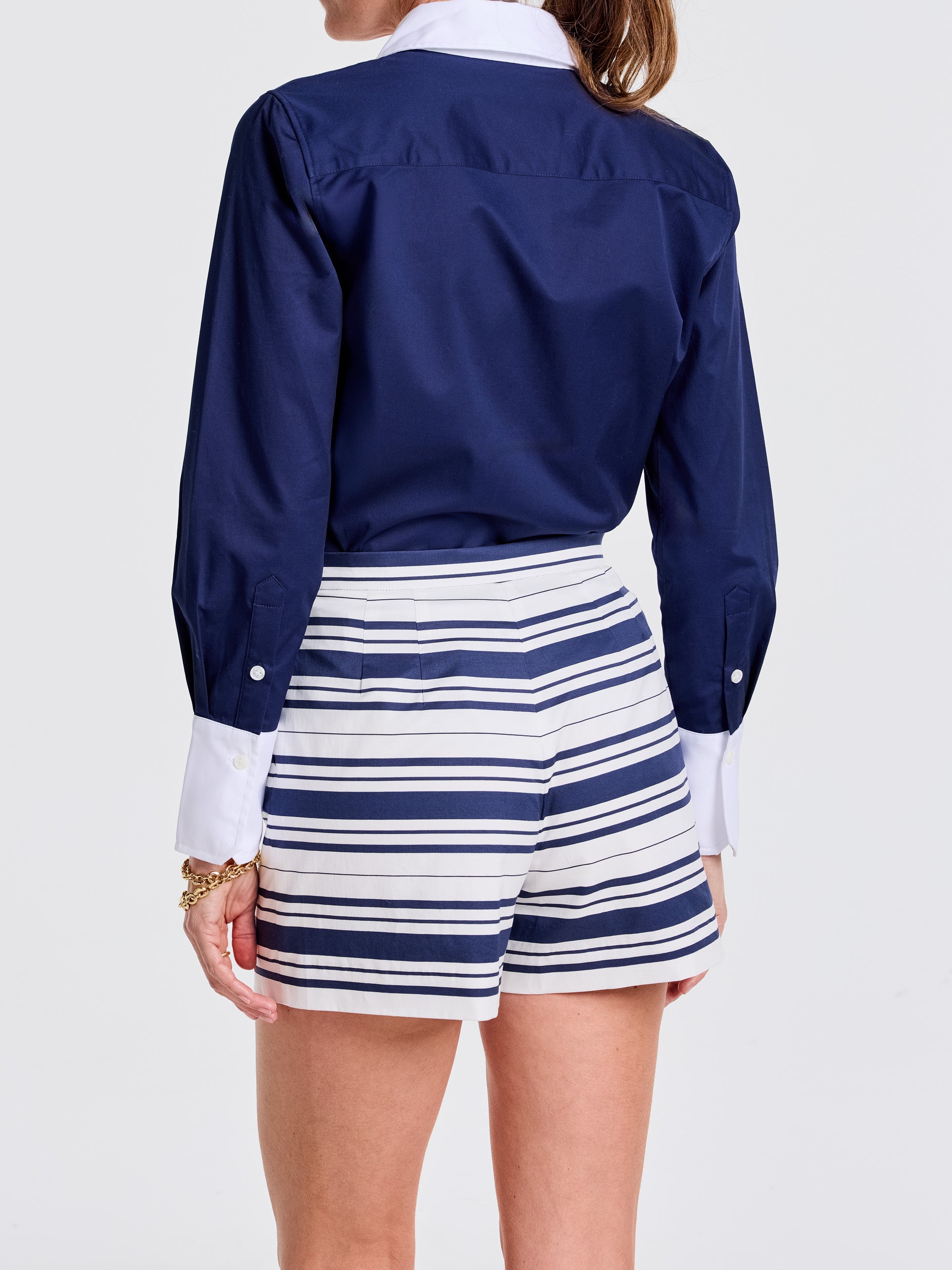 Woman wearing Emily Shorts in Mariner Stripe by J.McLaughlin, paired with a navy blouse featuring white cuffs, showcasing effortlessly stylish and enduring designs for a destination of defining style. Life, Well-Lived.